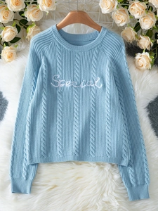 Detalle de jersey de punto trenzado azul claro con bordado blanco 'Special' y cuello redondo