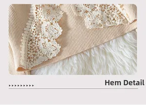 Detailed close-up of apricot knitted sweater hem with elegant white lace stitching