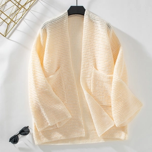 Détail du gilet en maille ajourée crème avec de grandes poches et une texture tricotée