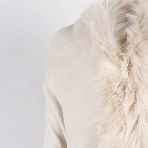 Close-up of fluffy faux fur collar and textured knit fabric on a beige poncho sweater