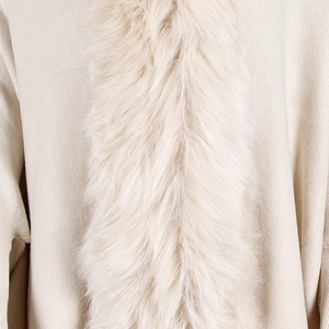 Close-up of knit fabric and soft cream faux fur trim detailing on the tassel poncho