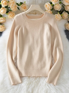 Detailed texture of beige ribbed knit sweater on a hanger with soft floral background