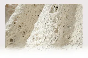 Detailed close-up of cream white crochet knit fabric with elegant floral hollow patterns