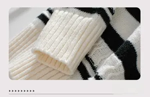 Close-up of black and white striped knit sweater showing elongated ribbed cuff details