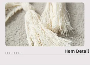 Detailed close-up of cream knit shawl fringe with natural cotton fiber texture
