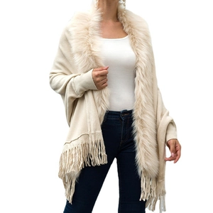 Elegant beige knit poncho featuring a plush faux fur collar and decorative fringe hemline