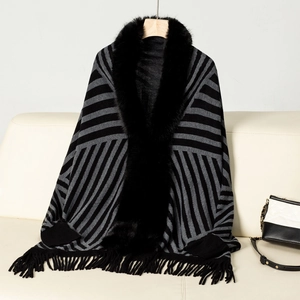 Detail of striped knit poncho featuring elegant black faux fur collar and fringe hem