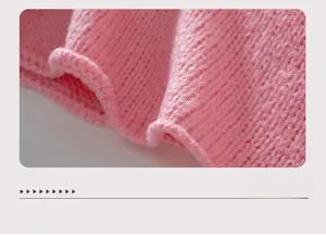 Dettaglio dell'orlo in maglia grossa di un maglione rosa con scollo a V morbido