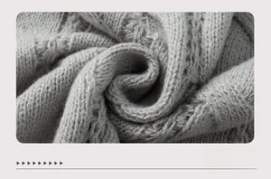 Detailed close-up of light gray cable knit fabric with a chunky twisted texture
