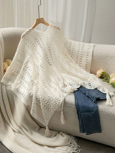 Detail of bohemian cream knit poncho featuring intricate hollow patterns and fringe trim