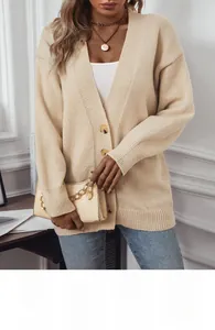Détails d'un gilet en maille beige avec boutons ambrés et texture douce de qualité