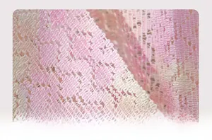 Macro view of pink and beige knitted bohemian lace fabric showing detailed hollow textures