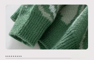 Close-up of green knit sweater cuff with white geometric pattern and ribbed texture