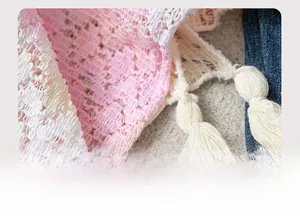 Close-up of pink and white gradient crochet lace hem with fringe tassels and soft fiber texture