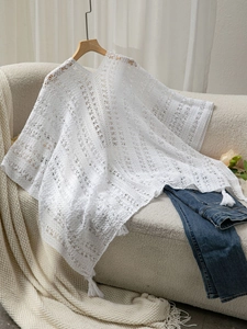 Close-up of white bohemian crochet shawl featuring intricate hollow geometric lace patterns