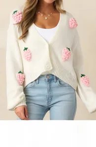 Détail des appliques de fraises 3D sur un cardigan en tricot blanc à col en V pour femme