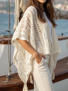 Close-up of cream crochet shawl featuring intricate geometric patterns and long tassel fringe