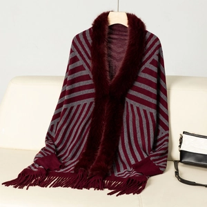 Detail of burgundy and grey striped knit poncho featuring a plush faux fur collar and tassels