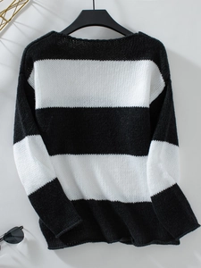 Dettaglio della morbida trama a maglia di un maglione a righe bianche e nere con polsini