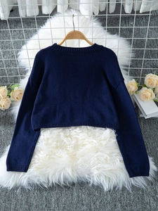 Close-up of deep blue cropped knit sweater showing ribbed cuffs and soft texture