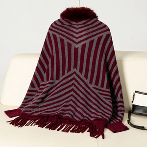 Detail of red and grey striped knit poncho with faux fur collar and fringe trim on sofa