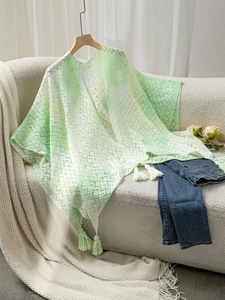 Close-up of light green lace shawl featuring hollow patterns and elegant tassel details