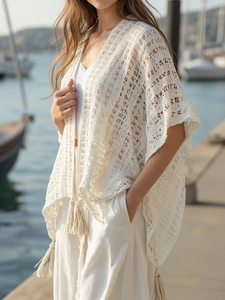 Detail of bohemian ivory crochet cardigan featuring intricate cutouts and fringe tassels