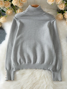 Close-up of ribbed cuffs with decorative buttons on a grey knit turtleneck sweater