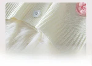 Détail de l'ourlet du cardigan en maille blanche avec bouton et fleur fraise au crochet