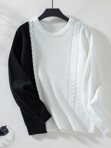 Close-up of contrast knit sweater featuring intricate cable patterns and ribbed cuffs