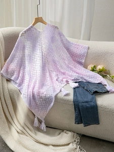 Detail of purple gradient crochet poncho featuring delicate lace patterns and white tassels