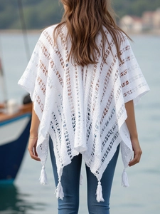 Detail of white hollow crochet knit shawl featuring bohemian tassels and V-shaped patterns
