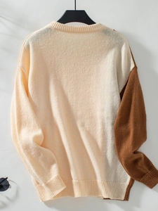 Detail of chunky cable knit texture on a contrast color-block crewneck sweater