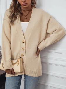 Détail du cardigan en maille beige avec boutons marbrés et poignets côtelés