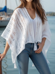 Close-up of white crochet knit kimono with detailed hollow pattern and tassel fringe