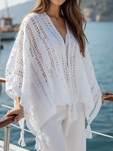 Close-up of white crochet beach cover-up with delicate hollow knit and tassel fringe details