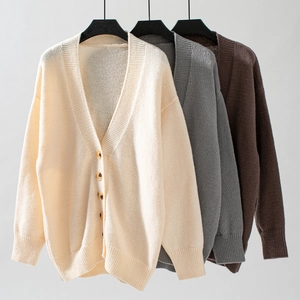 Gros plan de gilets en maille beige, gris et marron montrant les poignets côtelés et le col en V