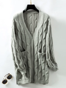 Close-up of light grey cable knit cardigan with texture, pockets, and side slit detail