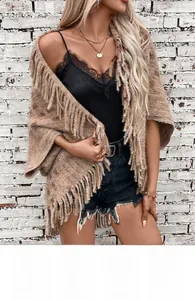 Detail of a brown knit plaid shawl featuring fringe tassels and a chunky woven texture
