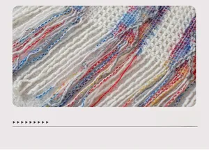 Detailed macro view of knitted poncho hem with colorful stripes and fringe tassels