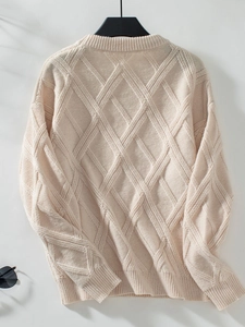 Close-up of beige cable-knit sweater featuring diamond patterns and ribbed crew neck