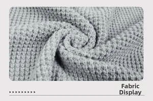 Nahaufnahme der hellgrauen Waffelstrick-Stoffstruktur einer Damen-Strickjacke