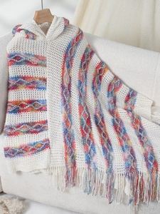 Detail of white knit poncho with colorful wave patterns and long bohemian style tassels