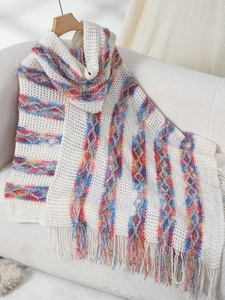Detail of knit poncho with colorful vertical stripes and long tassel fringe trim