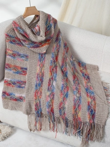 Detailed close-up of colorful striped knit poncho with long tassel fringe and texture