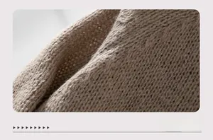 Close-up of oatmeal chunky cable knit sweater fabric showing texture and soft material