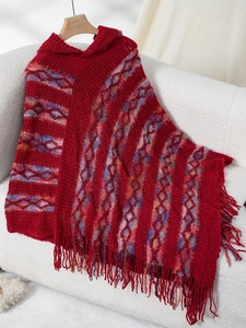 Detailed knit texture of red hooded poncho with bohemian pattern and tassels