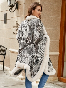 Detail of knit poncho featuring peacock pattern and thick faux fur trim on the edges