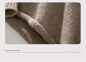 Detail of loose-fit brown sweater featuring thick knit texture and rolled hem edge