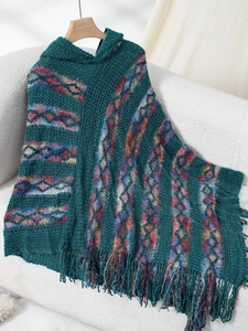 Close-up of knit poncho featuring dark green texture with colorful geometric patterns